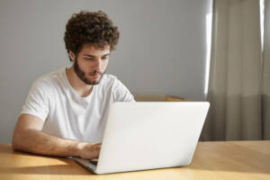 people electronic devices technology concept candid shot serious handsome young male freelancer using free wifi laptop while working remotely from home office having focused look